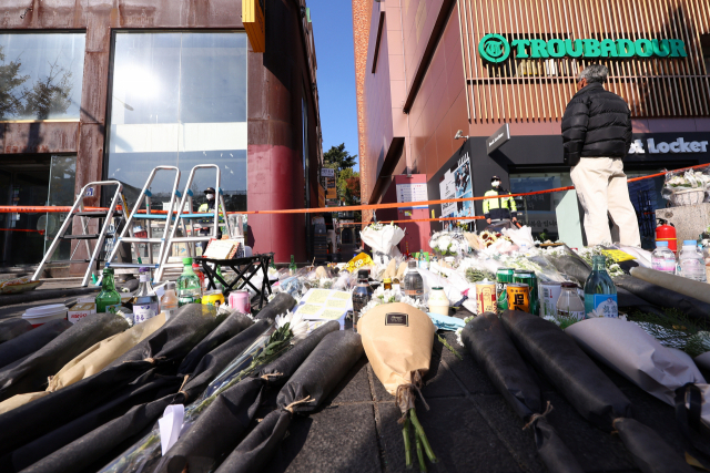 6일 오후 서울 용산구 이태원역 인근 사고 현장 골목길에 설치된 경찰통제선 앞에 추모객들이 준비해온 조화와 추모 물품들이 놓여 있다. 연합뉴스
