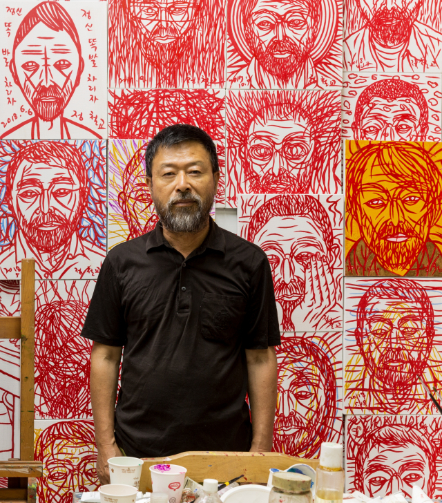 정철교 작가가 자신의 자화상 그림들 앞에 서있다. 작가 제공