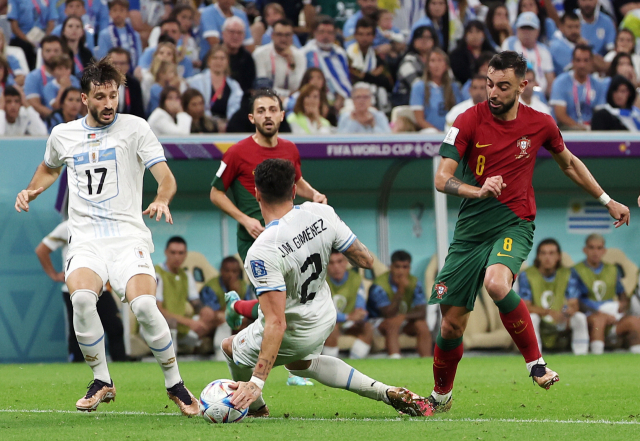 지난달 28일(현지시간) 도하 루사일 스타디움에서 열린 2022 카타르 월드컵 조별리그 2차전 포르투갈과 우루과이의 경기에서 포르투갈의 브루누 페르난드스(오른쪽)가 상대 수비수에게서 페널티킥을 얻어내고 있다. 페르난드스는 직접 페널티킥을 넣어 멀티 골을 기록했다. 연합뉴스