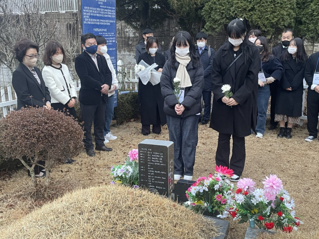 지난 14일 부산 금정구 영락공원에서 열린 이수현 씨 추모행사에서 학생들이 그의 묘에 헌화하고 있다. 사진 왼쪽은 이수현 씨 어머니와 여동생.