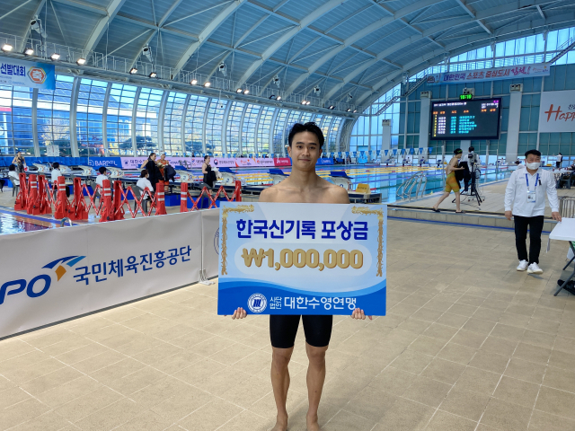 제13회 김천 전국수영대회 남자 일반부 접영 50ｍ 결승에서 한국 타이기록으로 우승한 백인철이 100만 원의 포상금 패를 들고 포즈를 취하고 있다. 대한수영연맹 제공