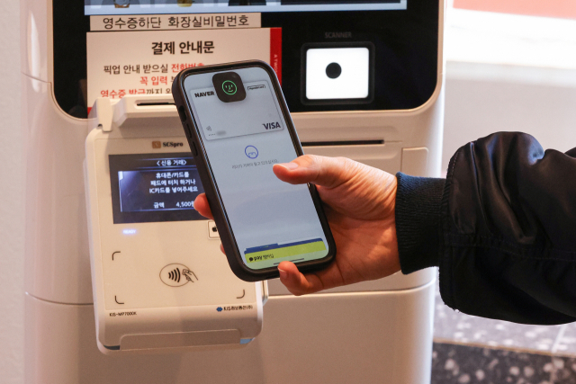 애플이 간편결제서비스 ‘애플페이’ 서비스를 21일 한국에서 공식 출시했다. 애플페이는 아이폰, 애플워치, 아이패드 등을 통해 이날부터 국내 오프라인 가맹점과 온라인 등에서 사용할 수 있다. 이날 카페 키오스크에서 한 고객이 애플페이로 결제하고 있다. 연합뉴스