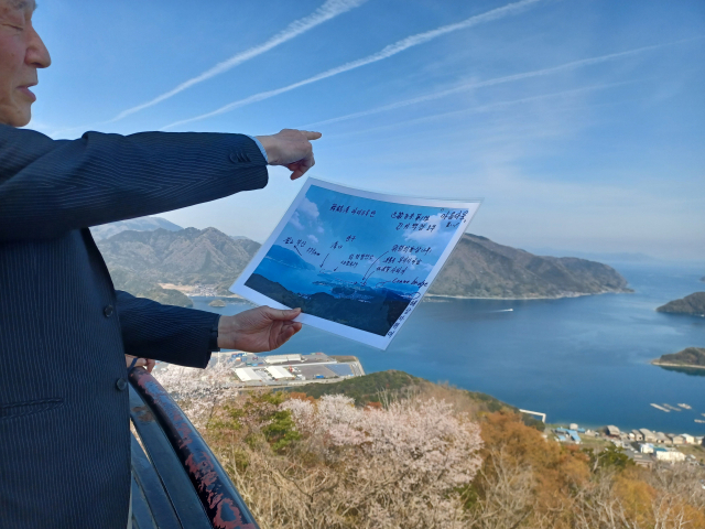 마이즈루 추도 모임의 하시모토 에이지 사무국장이 지난 4일 일본 마이즈루에서 우키시마호 침몰 장소 일대를 가리키고 있다. 우키시마호희생자추모협회 제공