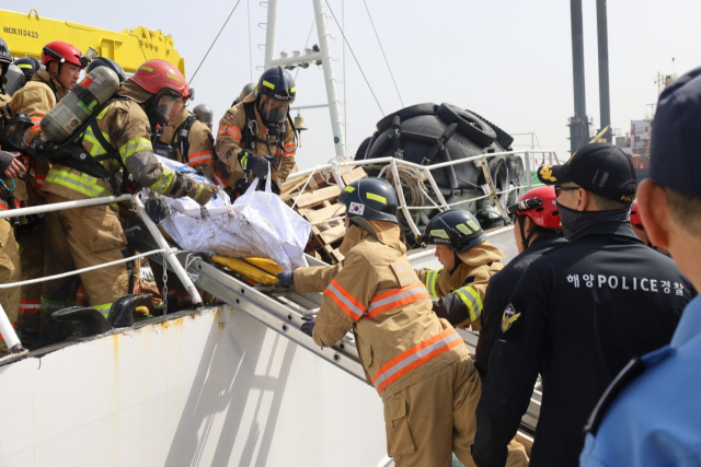 해경과 소방관들이 불이 난 러시아 어선에서 실종된 선원의 시신을 수습하고 있다. 울산소방본부 제공