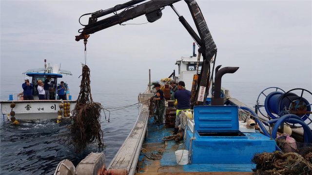 수산자원 보호를 유도하기 위한 수산자원직불금 제도의 지원 대상 선정 방식에 어민들이 반발하고 있다. 크레인 선박으로 해양 쓰레기를 수거하는 모습. 부산일보DB