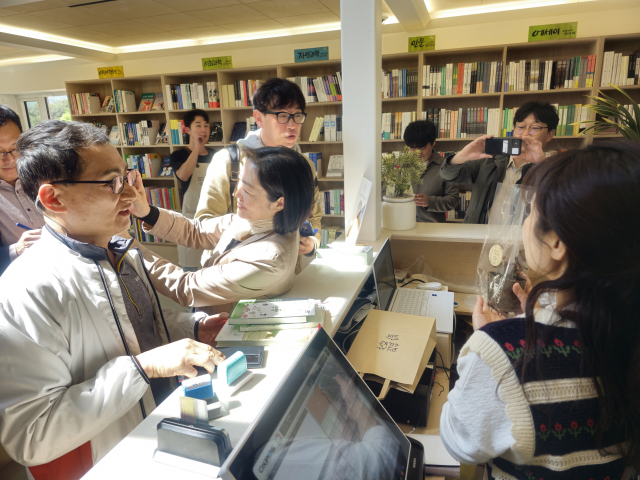 평산책방에서 외지인 1호 구매자인 수원에서 오신 50대 부부가 책 구매 선물인 새씩 모종을 배경으로 기념사진을 찍고 있다. 김태권 기자