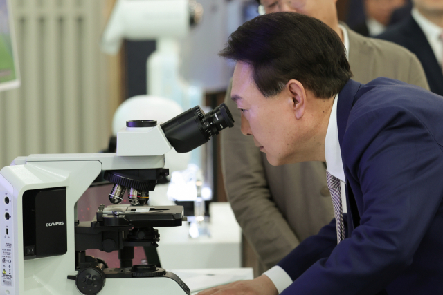 윤석열 대통령이 지난 1일 서울 강서구 서울창업허브 엠플러스에서 열린 제5차 수출전략회의에 앞서 KAIST 김찬혁 교수로부터 알츠하이머 단백질 치료제에 대한 설명을 들은 뒤 현미경을 보고 있다. 대통령실 제공.
