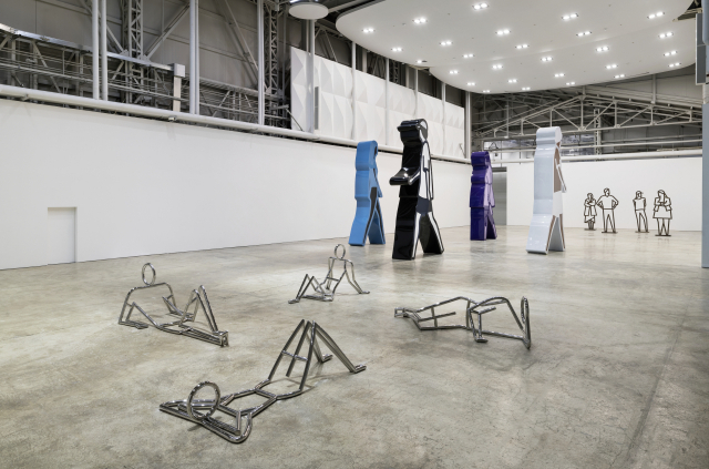 줄리안 오피 개인전 'OP.VR@Kukje/F1963.BUSAN' 설치 전경. 런던 공원에서 일광욕을 즐기는 사람을 표현한 스테인리스 스틸 조각(앞)과 부산의 걷는 사람을 표현한 대형 조각(가운데), 손을 숨기고 포즈를 취한 영국인의 모습을 옮긴 나무 조각(뒤)이 석천홀에 전시되어 있다. 국제갤러리 제공