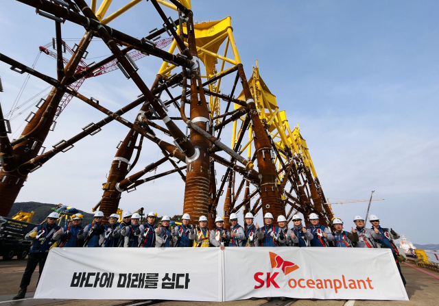 SK오션플랜트 임직원들이 수출을 앞둔 해상풍력 하부구조물 앞에서 기념촬영을 하고 있다. SK오션플랜트 제공