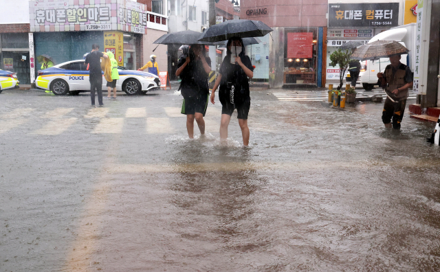 11일 오후 부산 수영구 우리은행 망미지점 앞 도로가 기습 폭우로 침수되면서 행인들이 물 위를 힘겹게 걸어가고 있다. 정종회 기자 jjh@