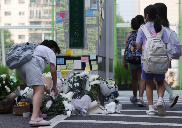 등교하던 한 학생이 20일 서울 서초구 한 초등학교 앞에 헌화하고 있다. 연합뉴스