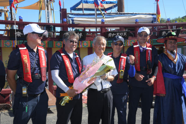 지난 4일 오후 일본 쓰시마시 이즈하라항 대주해운 앞 부두에서 열린 조선통신사선 입항 세리머니 도중 히타카쓰 나오키(왼쪽에서 세 번째) 쓰시마시장이 국립해양문화재연구소 홍순재(왼쪽에서 두 번째) 학예연구사에게 꽃다발을 전달하고 있다. 부산문화재단 제공