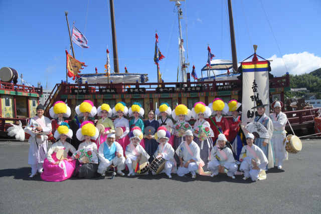6일 오후 일본 쓰시마에서 열린 '조선통신사 행렬 재현' 출발에 앞서 조선통신사선을 배경으로 기념사진을 찍고 있는 한국 측 참가자인 부산 춤패 배김새와 남산놀이마당 단원들. 부산문화재단 제공