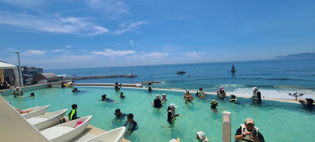 프리미엄 워터파크 ‘클럽디 오아시스’. 하늘과 바다가 맞닿은 80m 길이 인피니티풀은 해운대 바다와 주변 고층 건물 스카이 라인이 조화를 이루며 아름다운 풍광을 선물한다. 해운대 바다와 탁 트인 전망을 배경으로 사진을 찍는 이들이 많다.