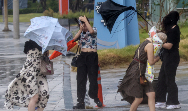 제6호 태풍 카눈이 북상 중인 9일 오후 부산 해운대해수욕장 해변로에 강한 바람이 몰아쳐 관광객들이 우산을 부여잡고 힘겹게 걷고 있다. 김종진 기자 kjj1761@