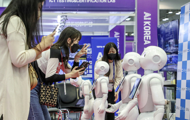 지난해 열린 ‘K-ICT Week in BUSAN 2022’에서 관람객들이 스마트 접객용 안내로봇을 살펴보고 있다. 부산일보DB