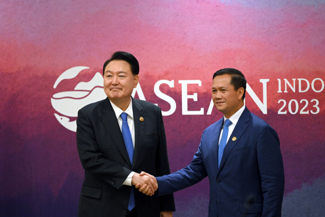윤석열 대통령이 7일(현지 시간) 인도네시아 자카르타 컨벤션센터(JCC)에서 열린 한국·캄보디아 정상회담에서 훈 마넷 캄보디아 총리와 악수하고 있다. 연합뉴스
