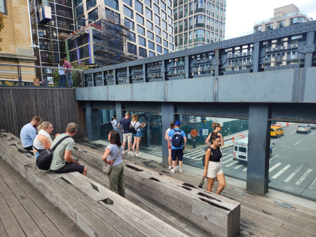 통창을 통해 뉴욕 거리 풍경을 보며 휴식을 취하는 시민들.