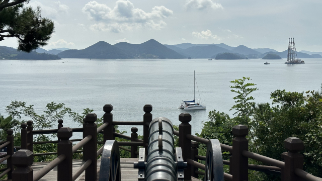 이순신공원에 설치된 천자총통 너머로 바라보이는 한산도대첩 전장. 지금은 평화로이 요트가 지난다.