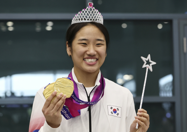 2022 항저우 아시안게임 대회 2관왕에 오른 배드민턴 안세영이 8일 인천공항을 통해 귀국한 뒤 왕관을 쓴 채 메달을 들어 보이고 있다. 연합뉴스