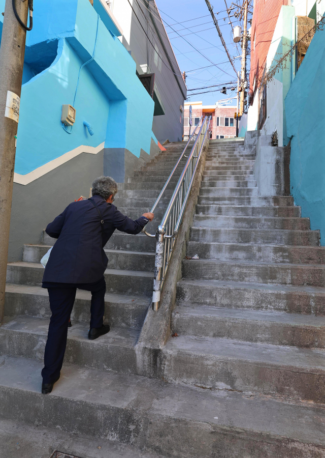 부산 서구청이 주도하는 산복도로 계단 길 정비 사업이 예산 확보난으로 시작부터 난항을 겪고 있다. 사진은 산복도로 가파른 계단을 오르는 노인의 모습. 정종회 기자 jjh@