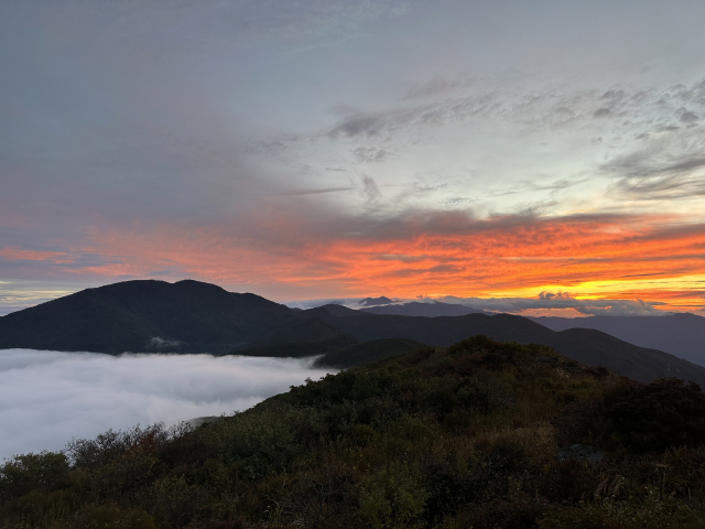 노고단 정상에서 바라본 일출. 가까이 반야봉(왼쪽)은 구름에 둘러싸였고, 멀리 천왕봉(가운데) 주변 하늘은 붉게 물들어 환상적이다.