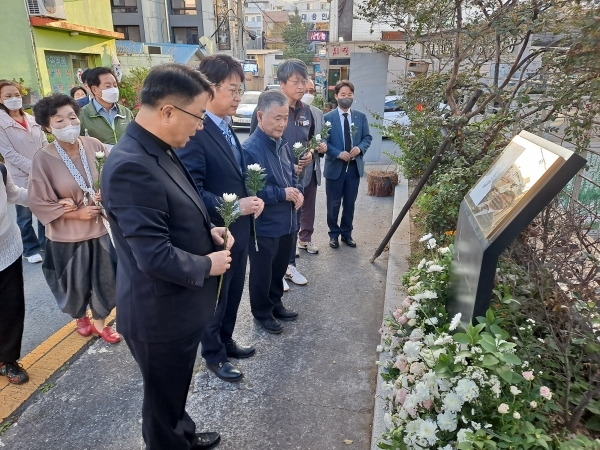 ‘열린사회희망연대’ 대표 백남해 신부 등이 마산 오동동 김명시 생가터에서 헌화하고 있는 모습. 산지니 제공