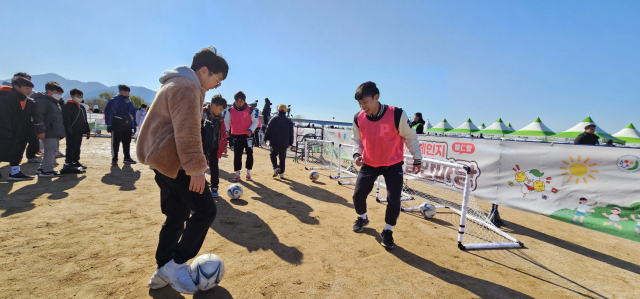 지난 18일 부산 사상구 삼락생태공원에서는 '아침체인지 어울림 한마당' 행사가 열렸다. 한 학생이 대학생 도우미와 함께 축구를 하고 있다. 김한수 기자 hangang@