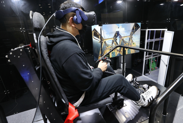 24일 서울 강남구 코엑스에서 열린 '2023 한국전자전'(KES)의 한 부스에서 관람객이 헬리콥터 조종 시뮬레이터를 체험하고 있다. 연합뉴스