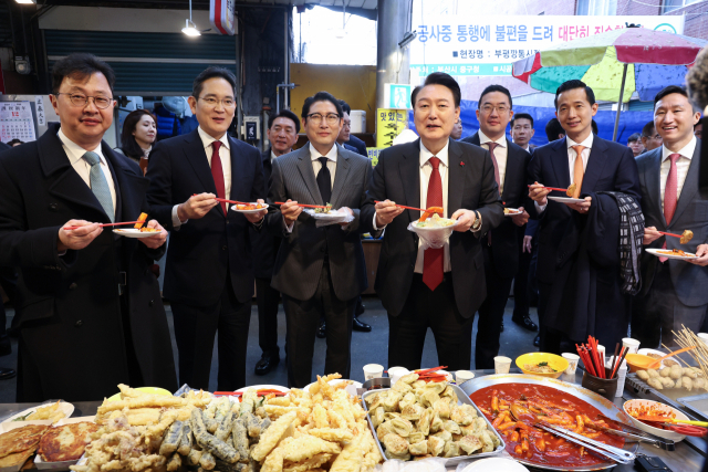 윤석열 대통령이 6일 부산 중구 깡통시장에서 기업 총수들과 함께 떡볶이 튀김 빈대떡을 시식하고 있다. 오른쪽 부터 정기선 HD현대 부사장, 김동관 한화그룹 부회장, 구광모 LG그룹 회장, 윤 대통령, 조현준 효성그룹 회장, 이재용 삼성전자 회장, 최재원 SK수석부회장. 연합뉴스