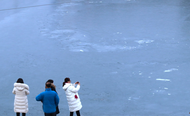 화천천을 찾은 관광객들이 산천어축제를 앞두고 꽁꽁 얼고 있는 얼음을 카메라에 담고 있다. 남태우 기자