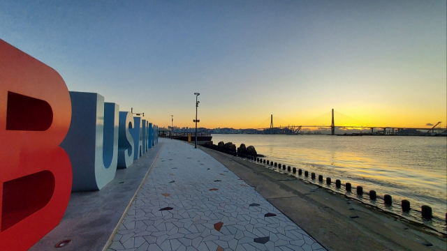 부산 북항 친수공원 수변 산책로의 영문 부산항 조형물(BUSAN PORT)에서 바라본 부산항대교. 다리 뒤쪽에서 여명이 걷히며 해가 떠오르고 있다. 김희돈 기자