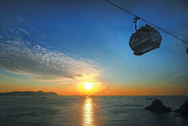 부산 서구 송도해상케이블카를 배경으로 찍은 일출 장면. 캐빈 안에서 새해맞이를 하는 것은 분명 새로운 경험이 될 것이다. 송도해상케이블카를 비롯해 부산·경남지역 케이블카 운영사는 1월 1일 해맞이객을 위해 평소보다 일찍 운영을 시작하고 별도의 이벤트도 준비 중이다. 송도해상케이블카 제공