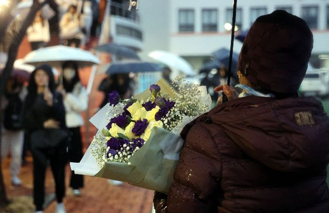 수능이 치러진 지난 11월 16일 부산 동래구 사직여고에서 한 학부모가 꽃다발을 들고 자녀가 시험장에서 나오기를 기다리고 있다. 부산일보DB