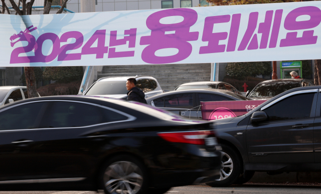 2024년 새해를 사흘 앞둔 29일 오후 광주 서구 쌍촌동에서 한 시민이 용띠해 갑진년 새해맞이 현수막 앞을 지나고 있다. 연합뉴스