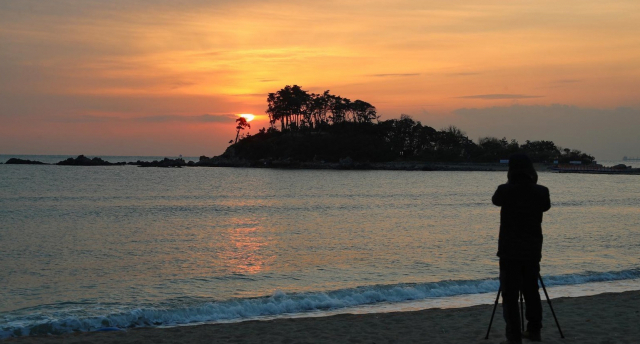 울산 울주군 진하해수욕장 인근 명선도 뒤로 붉은 해가 떠오르고 있다. 울산시 제공