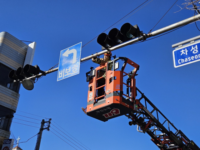 소방관이 23일 기장군 기장읍에서 강풍에 떨어지려 하는 신호등을 고정하고 있다. 부산소방재난본부 제공