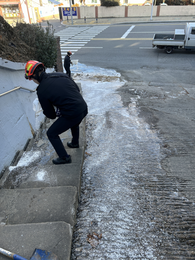 소방관이 23일 사하구 괴정동에서 얼음이 낀 도로에서 안전 작업을 하는 모습. 부산소방재난본부 제공
