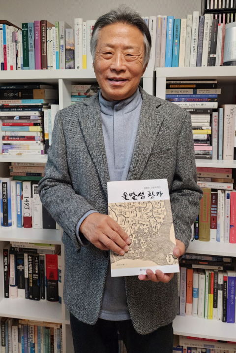 최화웅 씨가 자택의 서재에서 <울말섬 찬가>를 들고 있다.