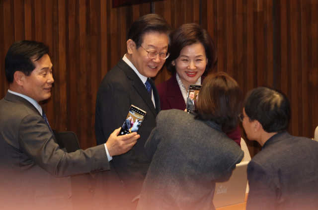 국민의힘 한동훈 비상대책위원장이 22일 중앙당사에서 열린 인재영입식에서 양종아 한뼘클래식기획 대표에게 당 점퍼를 입혀주고 있다(위쪽). 더불어민주당 이재명 대표와 의원들이 이날 국회 본회의장에서 대정부질문 시작 전 기념촬영을 하고 있다. 연합뉴스