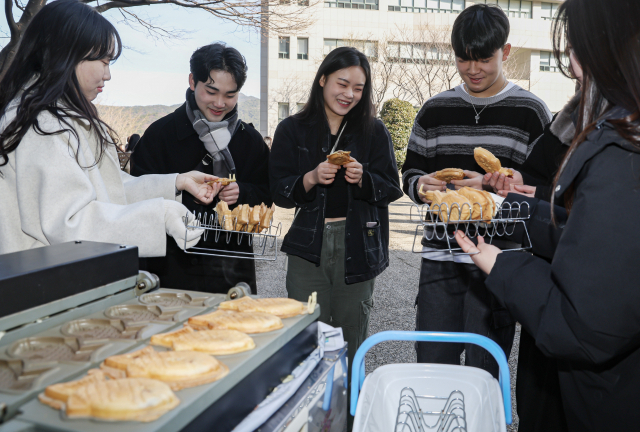 26일 부산 사상구 동서대학교 민석스포츠센터에서 열린 제33회 입학식에 입학 축하 붕어빵 나눔 행사가 열려 새내기 대학생들이 활짝 웃으며 붕어빵을 받고 있다. 김종진 기자 kjj1761@