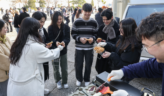 26일 부산 사상구 동서대학교 민석스포츠센터에서 열린 제33회 입학식에 입학 축하 붕어빵 나눔 행사가 열려 새내기 대학생들이 활짝 웃으며 붕어빵을 받고 있다. 김종진 기자 kjj1761@