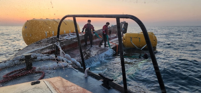 해양경찰 구조대가 전복된 선박을 예인하기 위해 침몰 방지용 리프트백을 설치하고 있다. 통영해양경찰서 제공