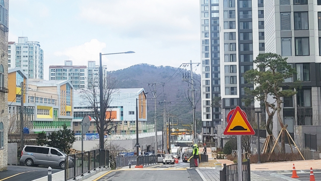 지난 4일 개교한 거제용산초등학교 통학로를 놓고 또 다시 논란이 일고 있다. 학교와 맞닿은 신축 아파트 단지가 등학교 시 입주민 자녀를 제외한 외부인 학생 출입을 막으면서 뒤편 아파트 단지 학생들이 가까운 지름길을 두고 먼 길을 둘러 학교로 향하고 있다. 사진 왼쪽이 용산초등, 오른쪽이 더샾디클리브 단지다. 김민진 기자