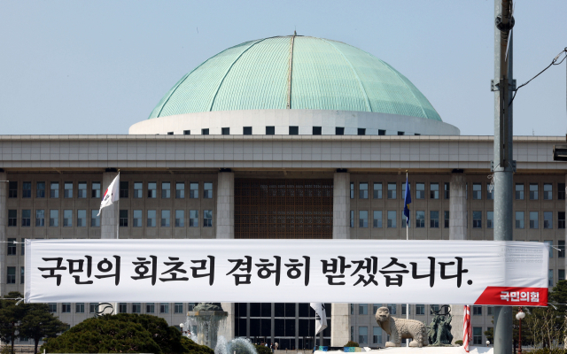 지난 12일 서울 여의도 국회의사당 앞에서 국민의힘이 설치한 현수막이 걸려 있다. 연합뉴스
