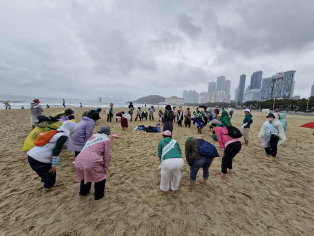 관광버스를 대절해 해운대 세븐비치 어싱 챌린지에 참가한 맨발걷기국민운동본부 대구지부 회원들이 동그랗게 원을 그린 채 사전 몸 풀기를 하고 있다. 김희돈 기자