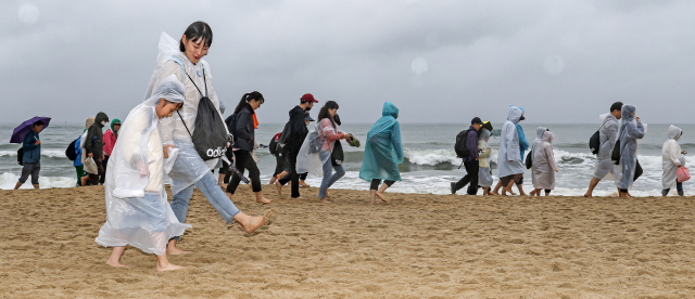 ‘맨발걷기 좋은 도시 부산 선포식 및 세븐비치 어싱 챌린지’가 21일 오후 부산 해운대해수욕장에서 열렸다. 참가자들이 박동창 맨발걷기국민운동본부 회장의 걷기 특강을 듣고 있다(위). 해안선을 따라 맨발로 걷는 참가자들. 김종진 기자 kjj1761@