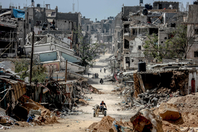 22일(현지시간) 가자지구 남부 칸유니스의 파괴된 건물들이 즐비한 도로를 팔레스타인인들이 걷고 있다. AFP연합뉴스