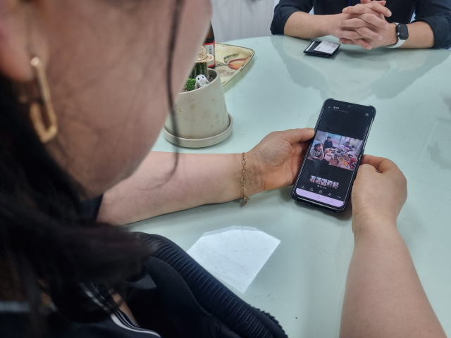 지난 10일 무연고 사망자 고 박동현(가명) 씨의 활동지원사 정영이 씨가 동현의 생일파티 사진을 보고 있다. 손혜림 기자 hyerimsn@