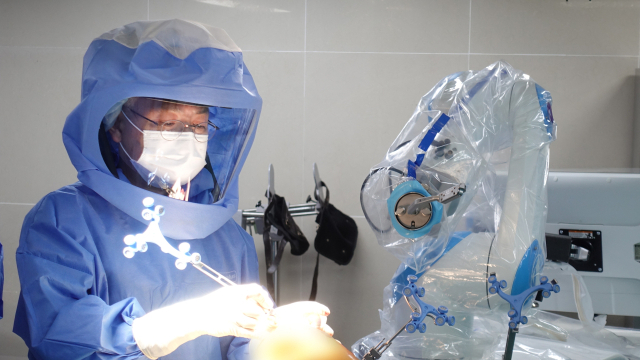 구포성심병원 관절센터 최태영 원장이 로봇수술 시스템으로 무릎 인공관절 치환술을 시행하고 있다. 작은 사진은 퇴행성 무릎 관절염 환자를 살펴보고 있는 김태우 과장. 구포성심병원 제공